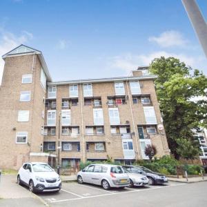a large brick building with cars parked in a parking lot at Cosy Home for 6 by Brixton Station in London
