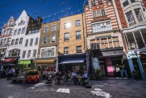 a group of people sitting at tables on a city street at Cosy Home for 6 by Brixton Station in London