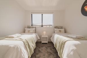 three beds in a white room with a window at Designer 2BR Flat - Outdoor Sitting & Cozy Ambiance in Christchurch