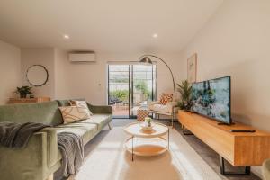 a living room with a couch and a tv at Designer 2BR Flat - Outdoor Sitting & Cozy Ambiance in Christchurch