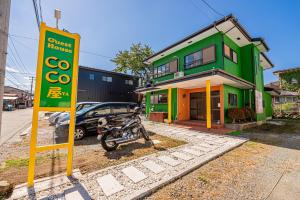 富士吉田市ゲストハウスCocoya的停在绿色建筑前面的摩托车