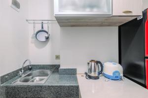 a kitchen counter with a sink and a microwave at Nice and Cozy Studio at Transpark Cibubur Apartment By Travelio in Depok