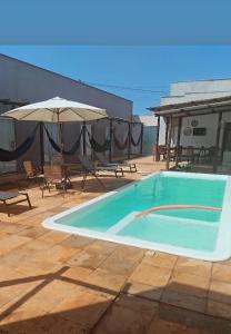 a swimming pool with chairs and an umbrella at Pousada Sol Gostoso in São Miguel do Gostoso