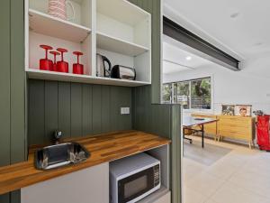 cocina con paredes verdes y encimera con microondas en Beachside Family Haven, en Inverloch