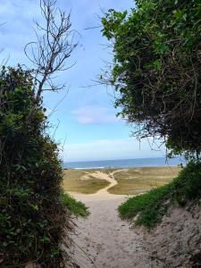 un camino de tierra que conduce a una playa con el océano en Sossego, en Florianópolis