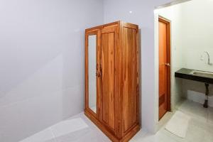 a bathroom with a wooden cabinet next to a sink at Widi Guest House near GWK Mitra RedDoorz in Jimbaran