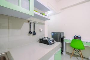 une cuisine avec un comptoir blanc et une chaise verte dans l'établissement Comfortable and Minimalist Studio at Bogorienze Apartment By Travelio, à Pamoyanan