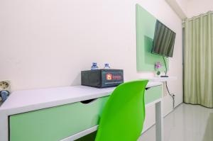 Cette chambre comprend un bureau et une chaise verte. dans l'établissement Comfortable and Minimalist Studio at Bogorienze Apartment By Travelio, à Pamoyanan