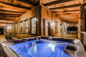 een groot blauw bad in een kamer met houten wanden bij Just Like Paradise cabin in Sevierville