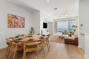 a dining room with a table and chairs and a couch at Sunsets Aldinga Beach, 4 king rooms, rooftop, incredible views in Aldinga Beach