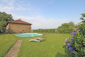a yard with a pool and a chair and a building at La feuillardiere in Dournazac