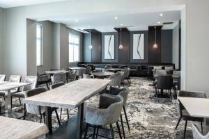 ein Esszimmer mit Tischen und Stühlen und Fenstern in der Unterkunft Fairfield Inn & Suites by Marriott Boston Logan Airport/Chelsea in Chelsea
