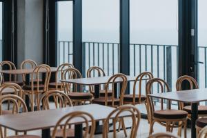 a row of tables and chairs in a room with windows at 緩慢大鵬灣 in Donggang