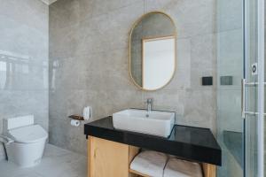 a bathroom with a sink and a toilet and a mirror at 緩慢大鵬灣 in Donggang