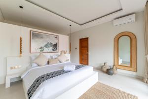 a white bedroom with a large bed and a mirror at Villa Kimaya Bali in Badung +71 photos