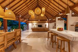 an open kitchen and living room with wooden ceilings at Villa Kimaya Bali in Badung