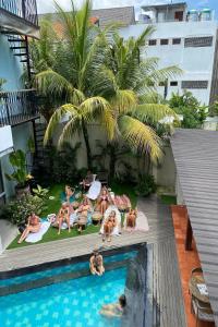 a group of people laying around a swimming pool at Coco & Pineapple Pants Hostel in Canggu
