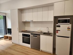 a white kitchen with a refrigerator and a sink at Discover Kingsford in Sydney