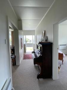 a living room with a piano and a room with a hallway at Seamstress Cottage in Marton