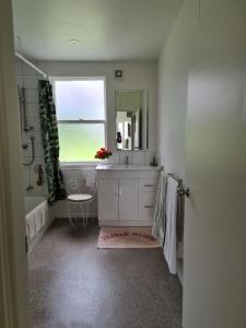 une salle de bain avec un lavabo, un miroir et une fenêtre dans l'établissement Seamstress Cottage, à Marton