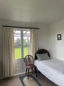une chambre avec un lit, une chaise et une fenêtre dans l'établissement Seamstress Cottage, à Marton