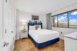 a white bedroom with a blue bed and a window at Bluewater Resort 502 in Myrtle Beach