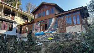 a house with a painting on the side of it at PineNest Cottages & Cafe in Jibhi