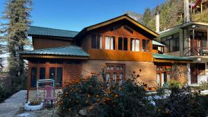 a large house with a green roof at PineNest Cottages & Cafe in Jibhi