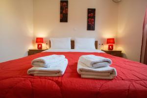 a bedroom with a red bed with towels on it at Baia Blu Apartments in Syvota