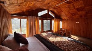 a bedroom with a bed in a room with windows at PineNest Cottages & Cafe in Jibhi +23 photos