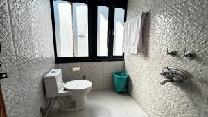 a bathroom with a white toilet and a window at PineNest Cottages & Cafe in Jibhi
