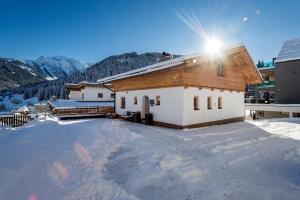 a house in the snow with the sun shining on it at Chalet Andreashof in Gerlos
