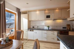 a kitchen with white cabinets and a table at Chalet Andreashof in Gerlos