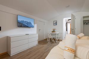 a white bedroom with a bed and a tv on the wall at Chalet Andreashof in Gerlos