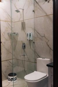 a bathroom with a glass shower with a toilet at Kesar The Saffron Homestay in Dehradun +9 photos