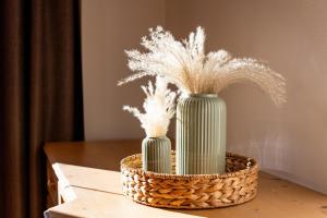 two green vases with white feathers in a basket at Chalet Andreashof in Gerlos