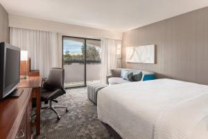 a hotel room with a bed and a desk and a television at Courtyard by Marriott San Jose South/Morgan Hill in Morgan Hill