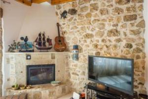 a living room with a television and a stone wall at Siorra Angelina Villa in Perítheia