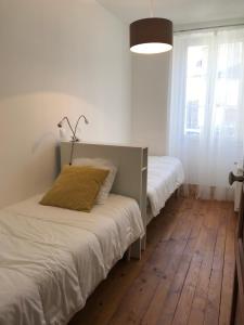 Un dormitorio con dos camas y una gran ventana. en L'Alexiane, Centre Luchon, parking gratuit, wifi, en Luchon