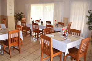 una sala da pranzo con tavoli bianchi e sedie in legno di Dove's Nest Guest House a Kempton Park