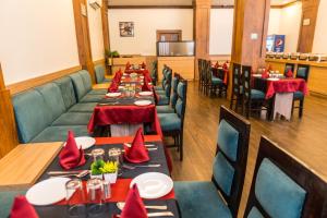 a dining room with tables and chairs with red napkins at Hotel The Royal Krishna in Katra