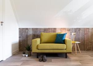 un sofá amarillo con una almohada azul en la sala de estar en B&B De Beiert en Delden
