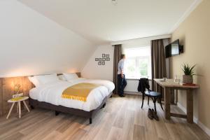 a hotel room with a bed and a person standing in a window at B&B De Beiert in Delden