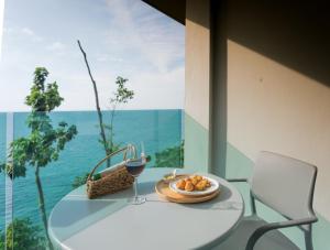 a table with a plate of food and a glass of wine at Cliff Lanta Suite-Koh Lanta Krabi in Ko Lanta