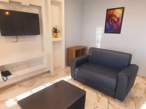 uma sala de estar com uma cadeira azul e uma televisão de ecrã plano em The Bohemian Lounge and hotel em Lekki