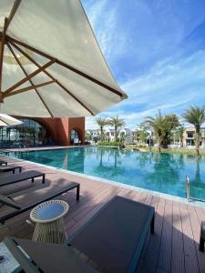 a large swimming pool with an umbrella and chairs at AnnA Home Novaworld Phan Thiết in Bình Tú