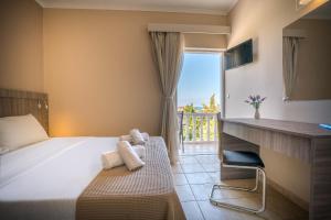 a hotel room with a bed and a desk and a window at Zakynthos Hotel in Tsilivi +22 photos
