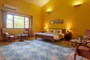a bedroom with a bed and chairs and a window at amã Stays & Trails Kihim Courtyard, Alibag in Alibag