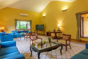a living room with blue furniture and yellow walls at amã Stays & Trails Kihim Courtyard, Alibag in Alibag