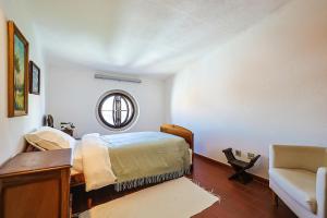 a bedroom with a bed and a chair and a mirror at Refúgio, casa típica Portuguesa in Setúbal